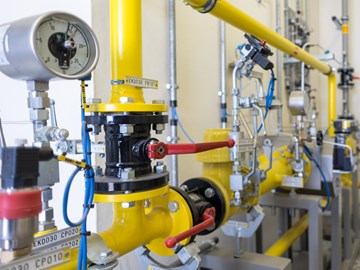 Seitliche Aufnahme einer Anlage mit gelben Rohren, roten Hebeln und Messanzeigen Seitliche Aufnahme einer Anlage mit gelben Rohren, roten Hebeln und Messanzeigen