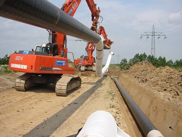 Bagger beim Verlegen von Rohrleitungen an einer Baugrube Bagger beim Verlegen von Rohrleitungen an einer Baugrube